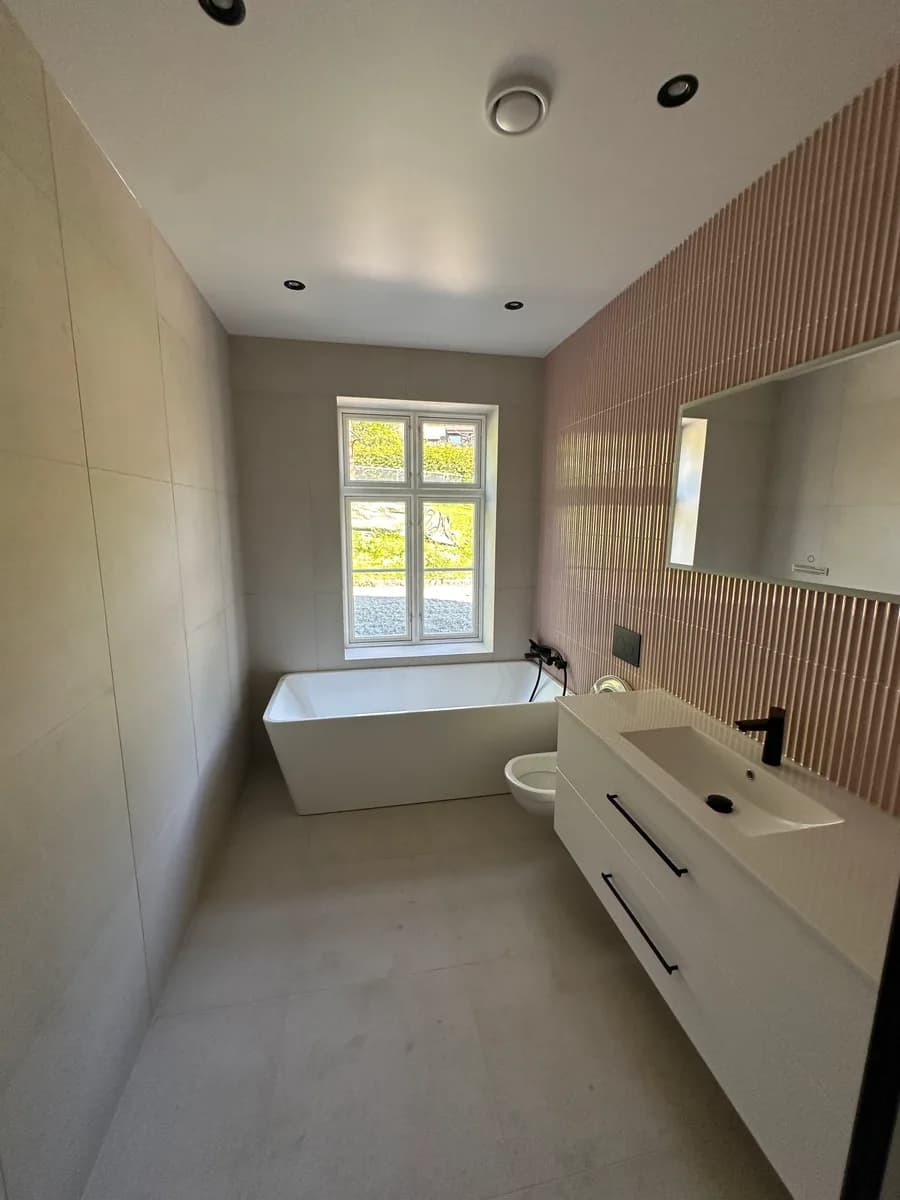 Lyst bad med dagslys fra vindu over badekaret